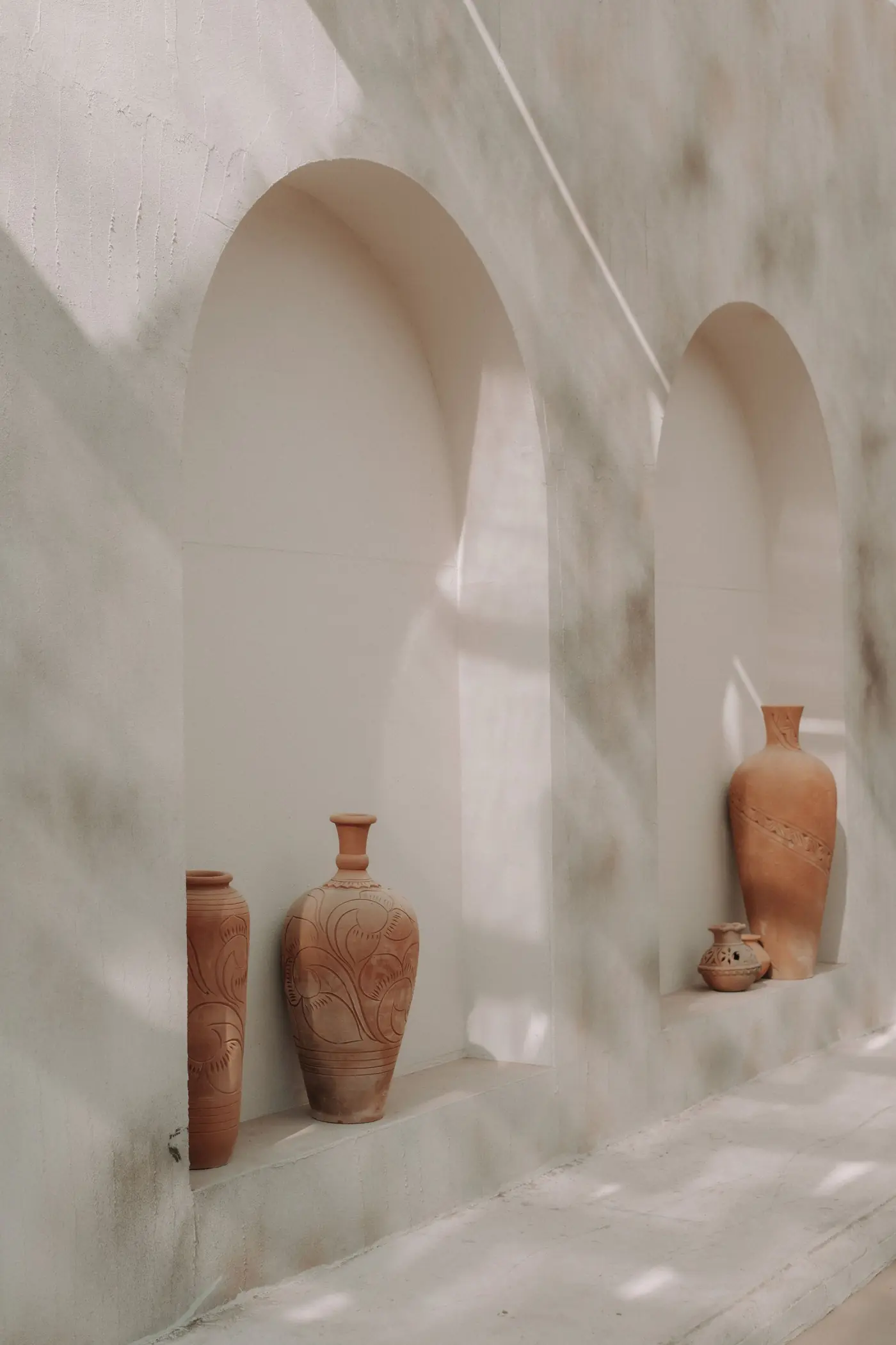 Terracotta vessels in a sunlit arched niche, material reference for One&Only Private Residences Al Maryah Island, Abu Dhabi